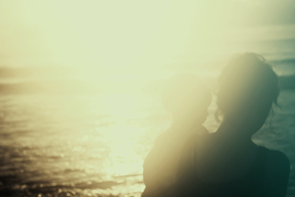 Inspiring woman and mother sitting by ocean with her child