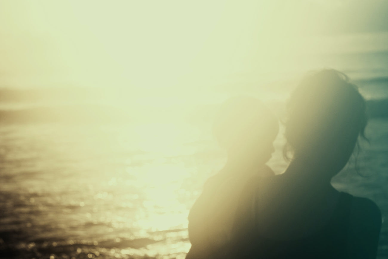 Inspiring woman and mother sitting by ocean with her child